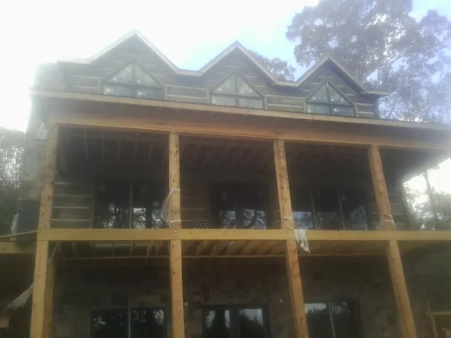 Dormers and porch framing on a large log home under construction — Roof Coating work by our crew in Forks