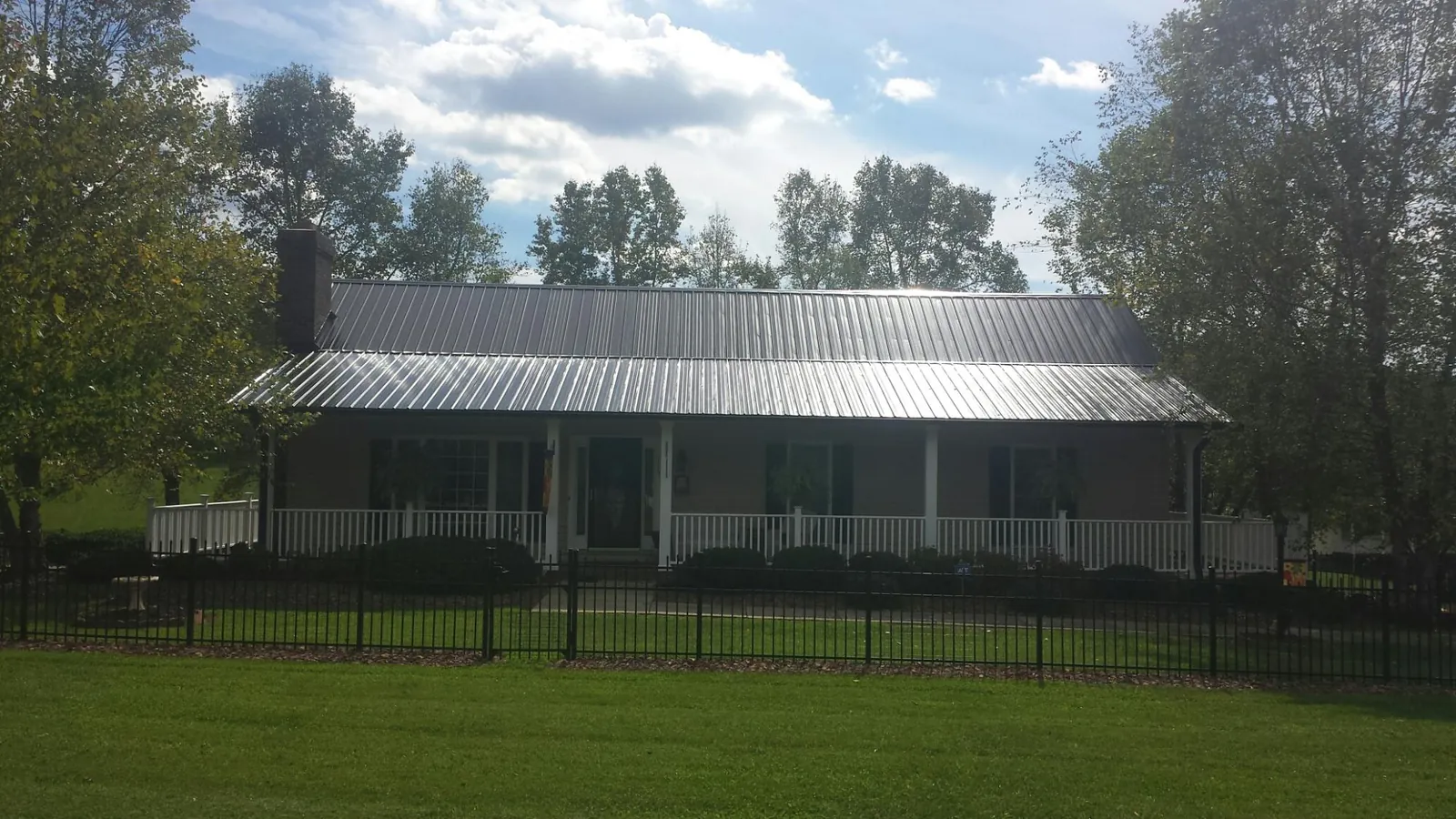 Gray metal roof on a brick ranch with a full width front porch — Gutter Guard Installation work by our crew in Forks