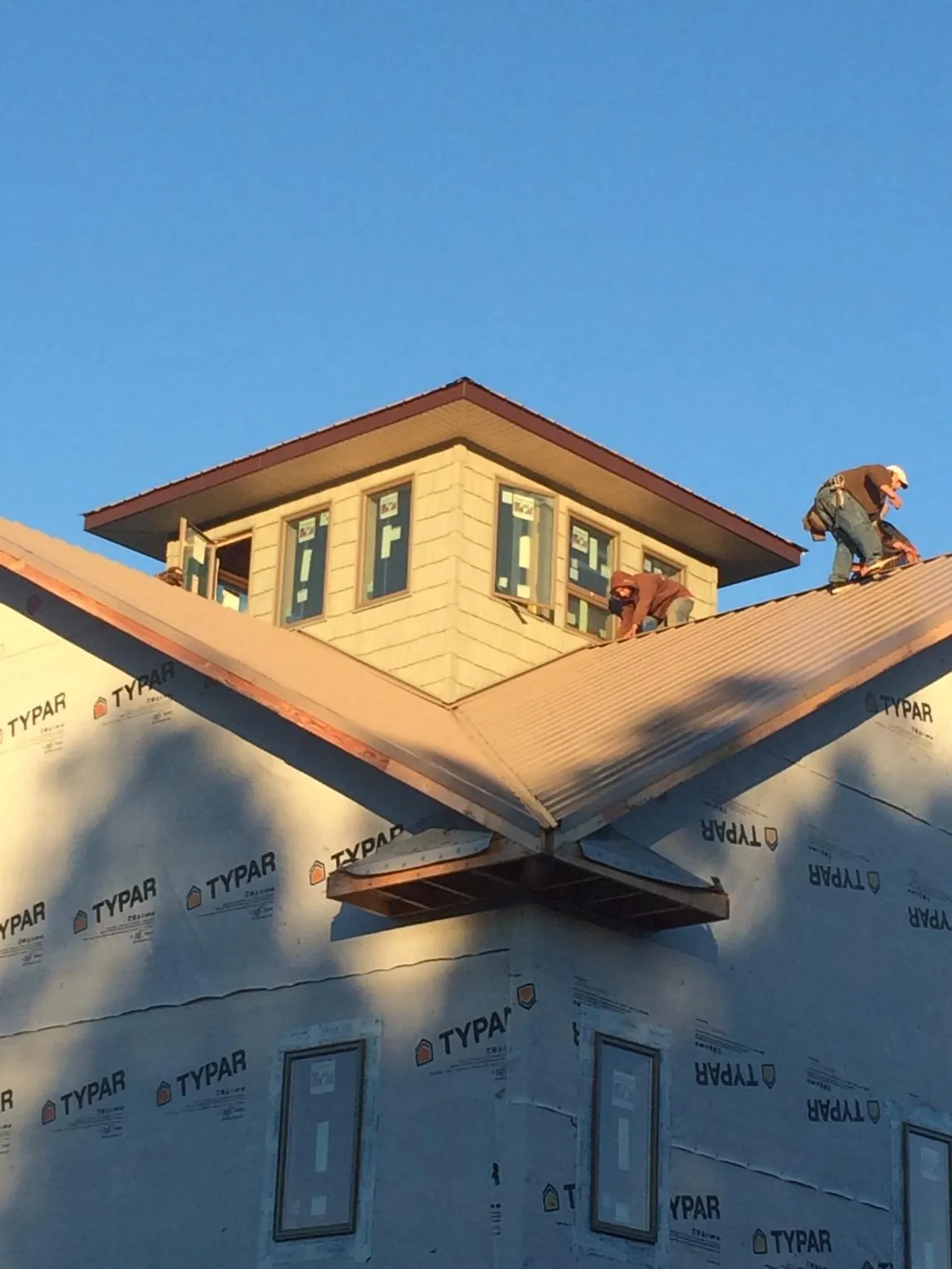 Roofers working around a rooftop cupola on a new metal roof at sunset — Roof Waterproofing in Forks by Roofing Brothers